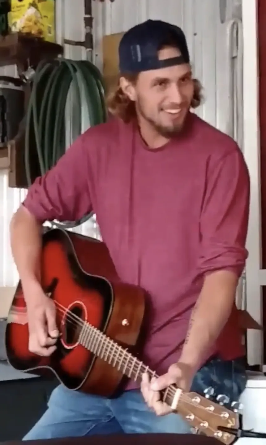 Gage Pitman smiling while playing guitar